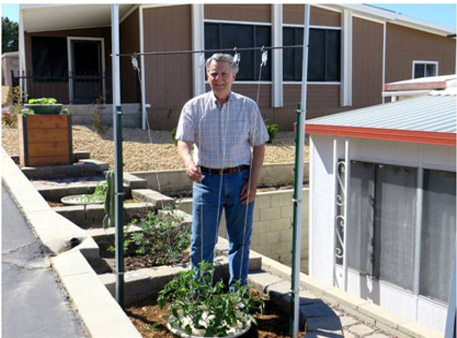 Bill McNeese naast zijn moestuin. De planten groeien in het warme Californië goed dankzij de Groasis Waterboxx